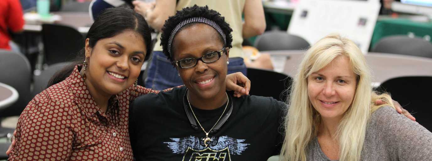 Three students look at the camera while having their photo taken.