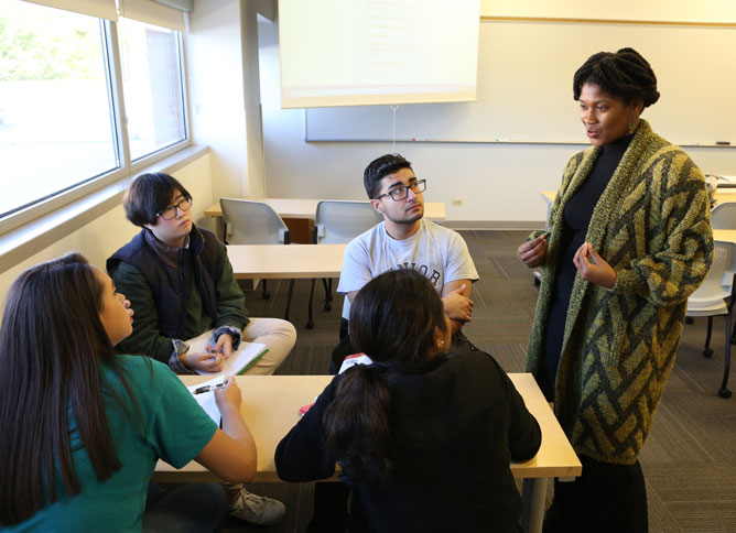 Teacher talking to a circle of seated students.