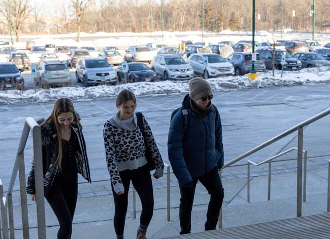 Three students walking up the steps to the Lee Center at Oakton College's Des Plaines campus.