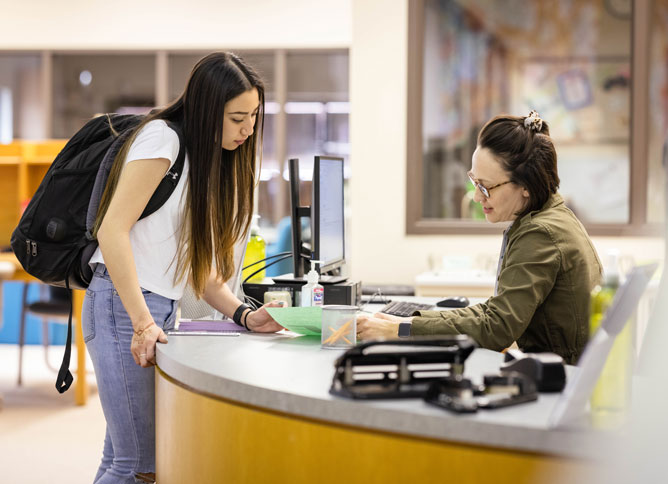 A student talking with a staff member at Oakton College's library.