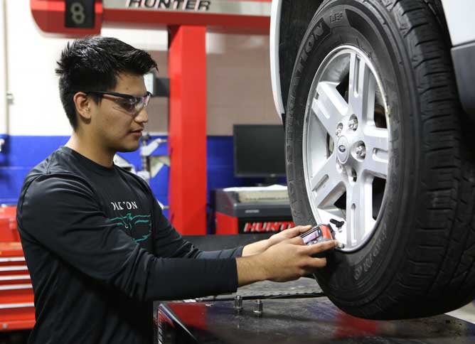 Automotive student working on a tire.
