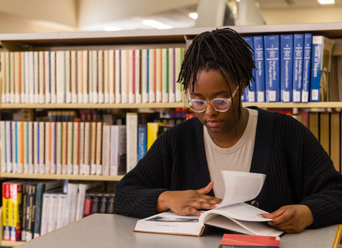 Student reading a book in the library.