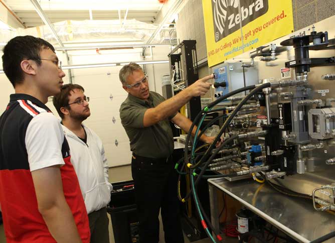 Manufacturing faculty showing students the back of a machine.