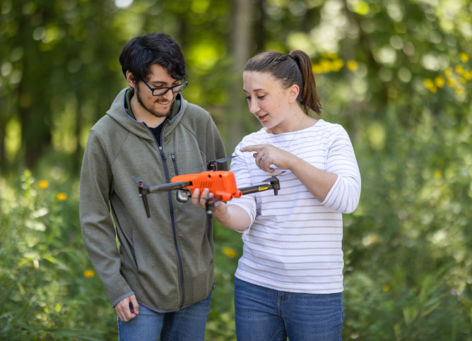 A pair of Oakton College students look over a drone.