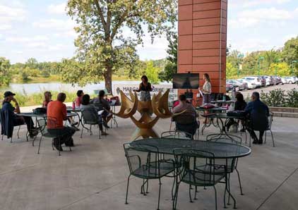 Appears to be Faculty and Staff members of Oakton College sitting at the Lee Center patio listening to a seminar.