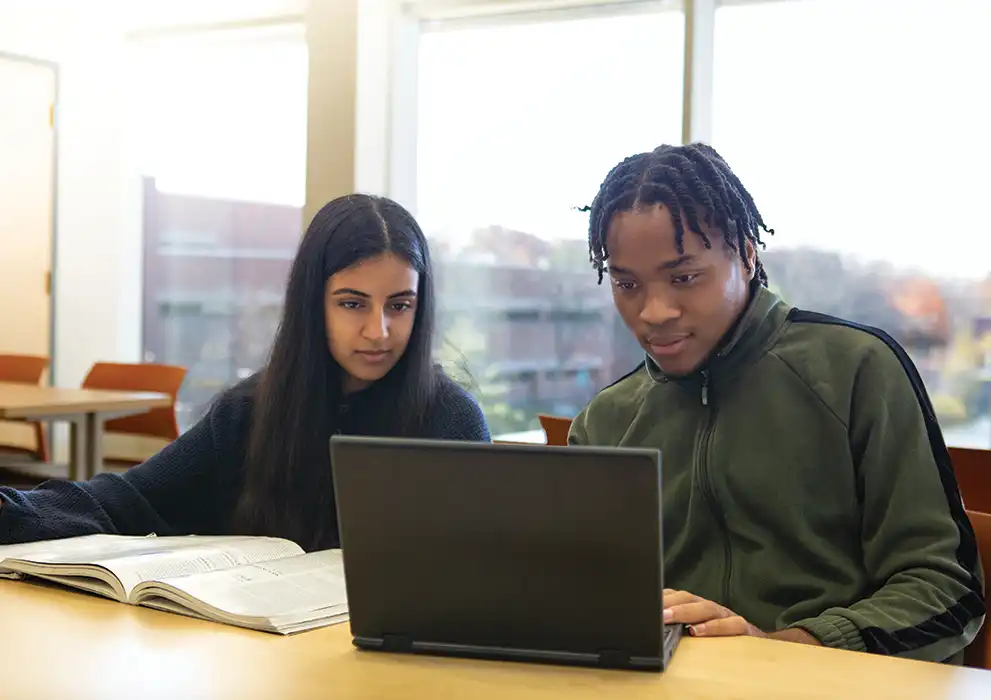 Two Oakton students look at a computer.