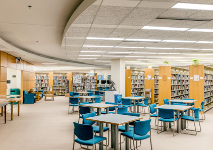 Stacks of books and tables at Des Plaines campus library