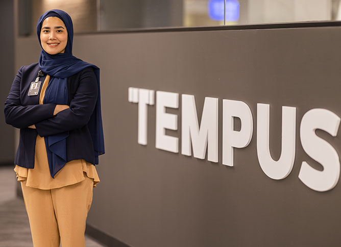 Oakton alum standing in front of workplace sign at Tempus.