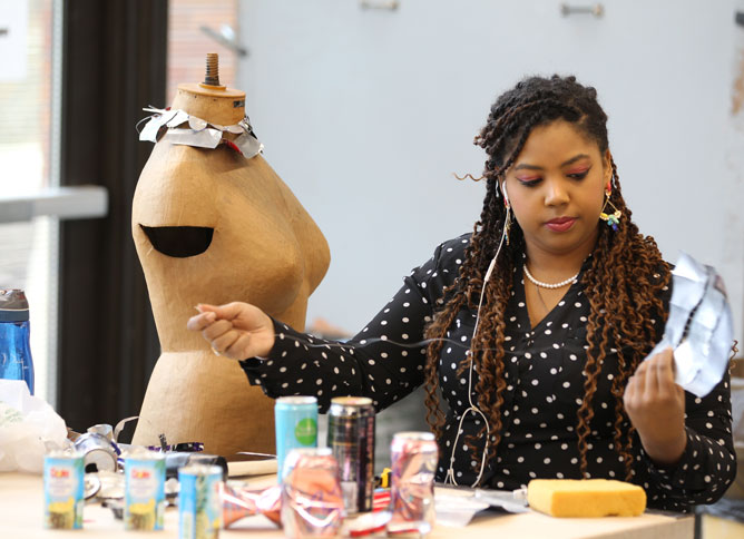 Student threading cans together in art studio.