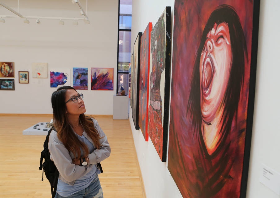Student gazes at painting of woman yelling.